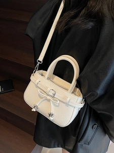 Sac à main blanc crème avec texture plissée et pendentifs étoiles sur fond en bois
