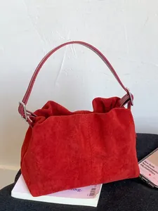 Red frosted suede bucket bag with vertical stitching and silver buckle on black stand