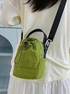 Grass green nylon drawstring bucket bag with black adjustable shoulder strap on model