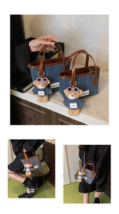 Detailed view of denim bucket bag with brown leather trim and cute bear charm accessory