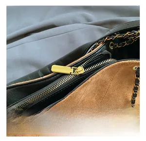 Détail du sac seau bicolore montrant la fermeture dorée et la texture du daim matelassé