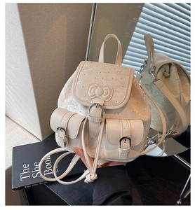 Detail of off-white mini backpack featuring embossed texture and a 3D bow with rhinestones