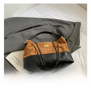 Gros plan d'un sac cabas matelassé en daim avec fermoir doré sur une veste de tailleur grise