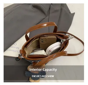 Interior view of denim bucket bag with brown leather handle and cute teddy bear charm