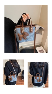 Détail du sac seau en denim bleu avec bordure en cuir marron et breloque chiot