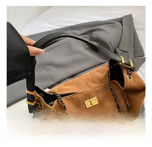 Détail du sac cabas en daim marron avec matelassage, fermoir doré et bandoulière chaîne