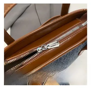 Close-up of premium silver zipper and brown leather trim on a denim bucket bag