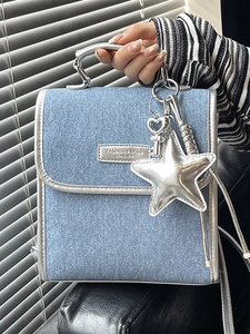 Light blue denim backpack with silver trim, metallic handles, and star charm accessory