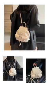Detail view of a cream-colored mini backpack featuring a bow design and stylish drawstrings