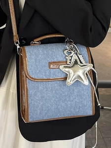 Blue denim and brown leather trim backpack with silver star charms on black background
