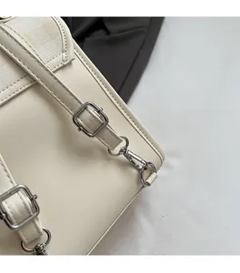 Dettaglio della fibbia in metallo argento e trama in pelle beige sulla tracolla