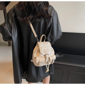 Detail view of mini cream leather backpack showing bow detail and adjustable straps on model