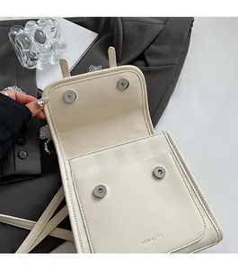 Dettaglio borsa a tracolla beige crema con doppie fibbie magnetiche e logo NINAITE