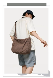 Side view of a brown canvas crossbody bag showing large capacity and adjustable strap