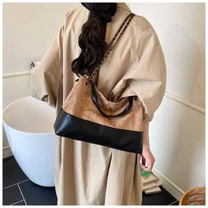 Gros plan du sac seau matelassé bicolore avec chaîne dorée et fermoir pivotant en métal