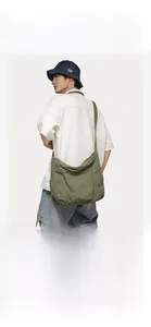 Army green large canvas bucket bag worn by a model in a casual crossbody style