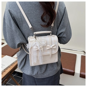 Détail d'un sac à dos beige à nœud avec tissu à carreaux et pendentif en dentelle perlée