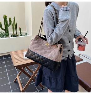 Close-up of quilted two-tone chain bag with gold metal clasp on a model shoulder