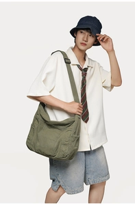 Detail of army green canvas bucket bag featuring a large main pocket and wide strap