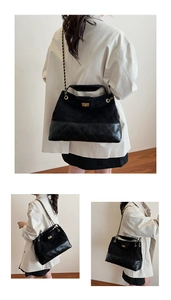 Close-up of black quilted shoulder bag featuring gold chain and turn-lock closure detail