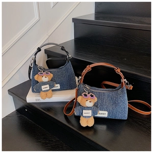 Detail von Denim-Beuteltaschen mit Teddybär-Anhängern auf einer Holztreppe