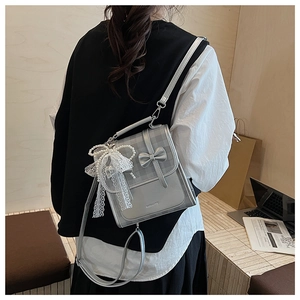 Gros plan du sac à nœud gris argenté avec perle en dentelle et texture cuir à carreaux