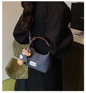 Detailansicht der Denim-Beuteltasche mit braunem Leder und niedlichem Plüschbär-Anhänger