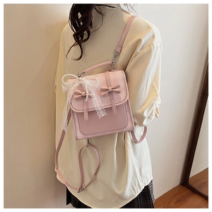Détail du sac à dos rose avec nœuds, dentelle et breloques en perles sous une lumière douce