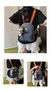 Dettaglio dello zaino in denim blu con spalline arancioni e ciondolo a forma di orso