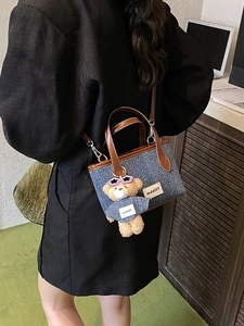 Denim mini bucket bag with leather trim and bear charm shown in lifestyle setting