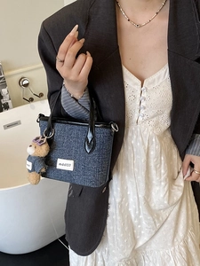 Blue denim bucket tote bag with leather handles and a cute teddy bear charm