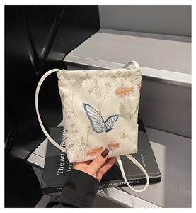 Détail du sac seau en satin blanc avec broderie papillon bleu et fleurs roses
