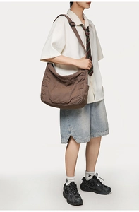 Brown canvas crossbody bag with multiple pockets and adjustable strap on male model