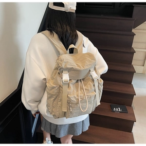 Detail of canvas backpack with drawstring closure and white resin buckles on khaki flap