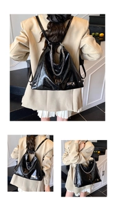 Close-up of black glossy leather tote bag with silver chain and metal hardware detail