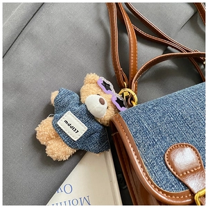 Close-up of denim patchwork bag with a cute plush bear charm wearing star sunglasses