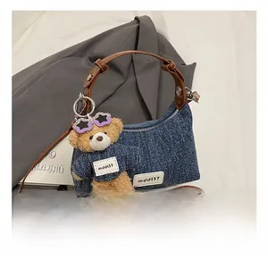 Detail der Jeans-Schultertasche mit Lederriemen und süßem Plüschbär-Anhänger Zubehör