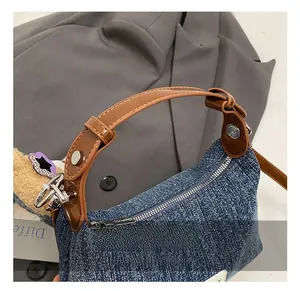 Detail der Jeans-Tragetasche mit braunem Ledergriff, silberner Metallschnalle und Nähten