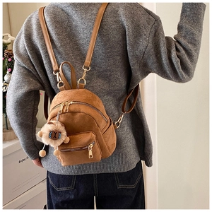 Detail of brown faux suede mini backpack with golden zipper and white sheep plush charm