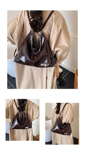 Three-way view of deep brown patent leather tote with silver chain and heart pendant