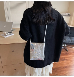 Détails brodés de fleurs blanches et papillons sur un petit sac seau gris élégant