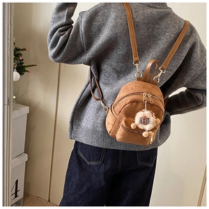 Brown suede mini backpack with cute white plush charm shown on person from behind