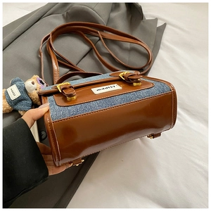 Detailed close-up of denim patchwork backpack with brown leather straps and gold metal buckle
