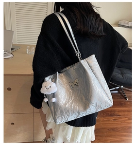 Silver tote bag with metallic crinkle texture, butterfly charm, and plush cloud pendant