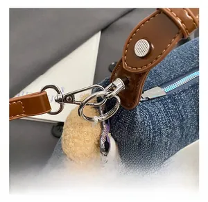 Detail von Silberhaken und braunem Lederriemen an blauer Denim-Beuteltasche