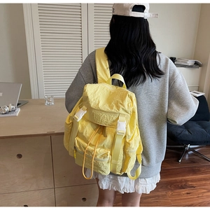Détail d'un sac à dos en nylon jaune avec texture froissée et boucle blanche