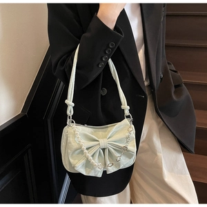 Detail of light green bow shoulder bag with pearl and metal flower decorative chain