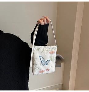 Gros plan détaillé sur la broderie papillon de ce sac seau blanc élégant