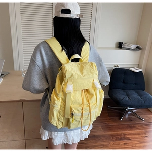 Close-up of yellow large capacity student backpack with white buckles and drawstring detail