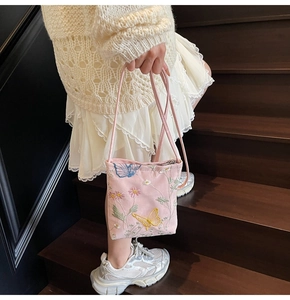 Détails de broderie papillon et fleurs sur un petit sac seau rose à bandoulière